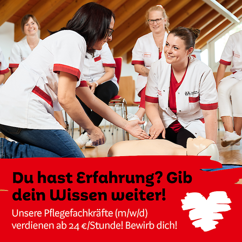 Eine Pflegefachkraft gibt in einem Erste-Hilfe-Kurs ihr Wissen an eine Kollegin weiter, während andere Teilnehmer in weißen Kitteln zuschauen. Der Text auf dem Bild wirbt für eine Stelle in der Pflege mit einem Stundenlohn von 24 €