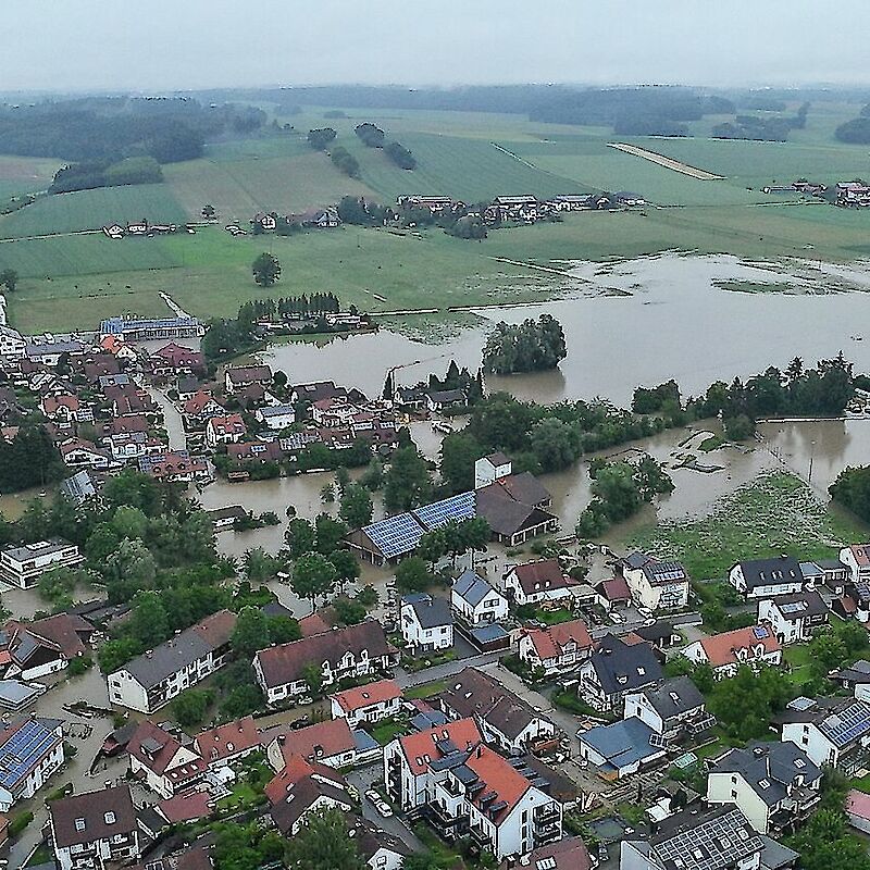 Luftaufnahme der vom Hochwasser betroffenen Gemeinde Hohenkammer in Bayern. Deutlich sichtbar sind überflutete Straßen, Häuser und landwirtschaftliche Flächen nach einem Unwetterereignis. Das Bild zeigt die Ausmaße der Überschwemmung und die Notwendigkeit schneller Hilfe und Spendenunterstützung. Ideal für SEO zu Hochwasser Hohenkammer, Flutkatastrophe Bayern 2024, Naturkatastrophenhilfe, Spendenaktionen und Klimafolgen in Deutschland.