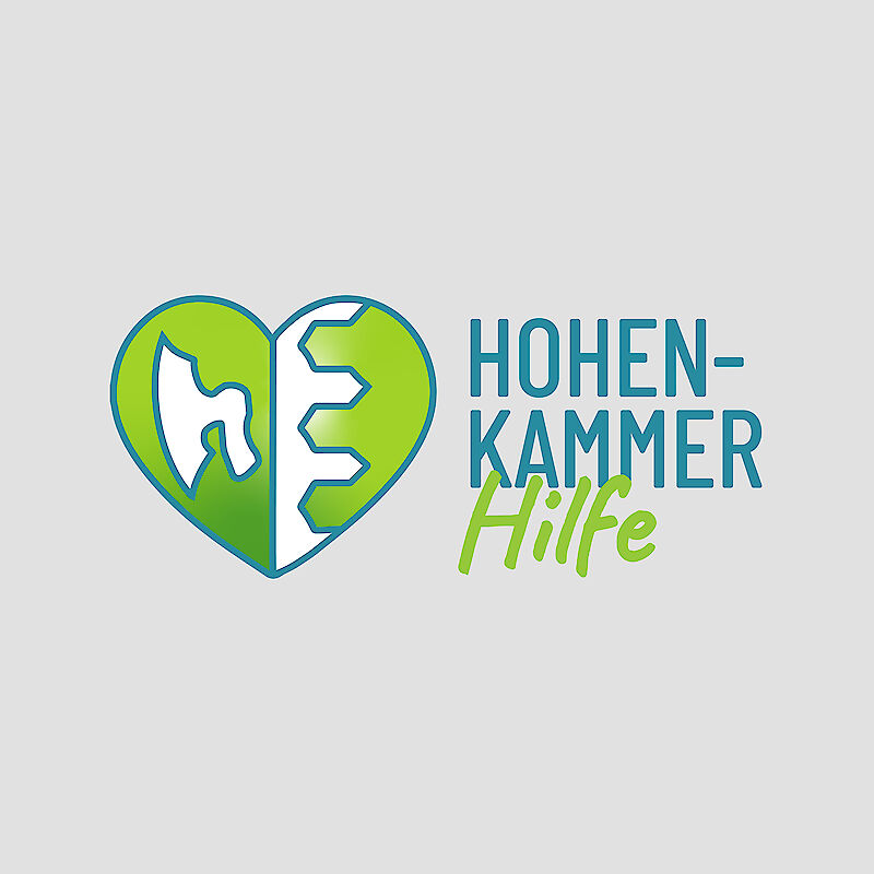 Logo der Initiative „Hohenkammer Hilfe“ mit einem grünen Herzsymbol – Symbol für Solidarität, ländliche Gemeinschaft und technische Unterstützung. Rechts daneben steht der Schriftzug „HOHENKAMMER Hilfe“ in blauer und grüner Schrift. Das Logo steht für regionale Hochwasserhilfe und gemeinnützige Unterstützung in der Gemeinde Hohenkammer.