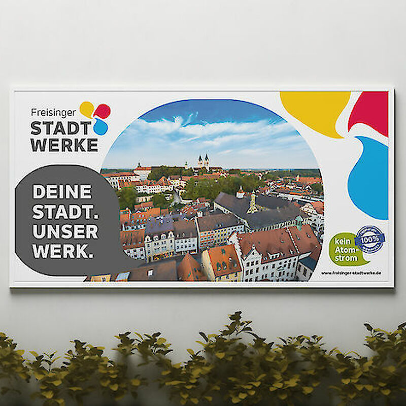 Werbeplakat der Freisinger Stadtwerke mit einer Stadtansicht von Freising, dem Slogan 'Deine Stadt. Unser Werk.' und einem Hinweis auf 100 % Ökostrom