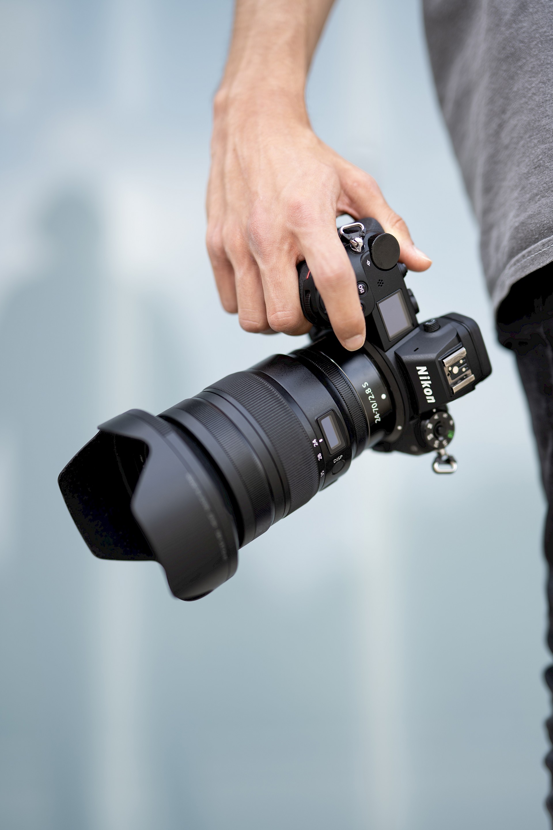 Nahaufnahme einer Hand, die eine professionelle Nikon-Kamera mit großem Objektiv hält