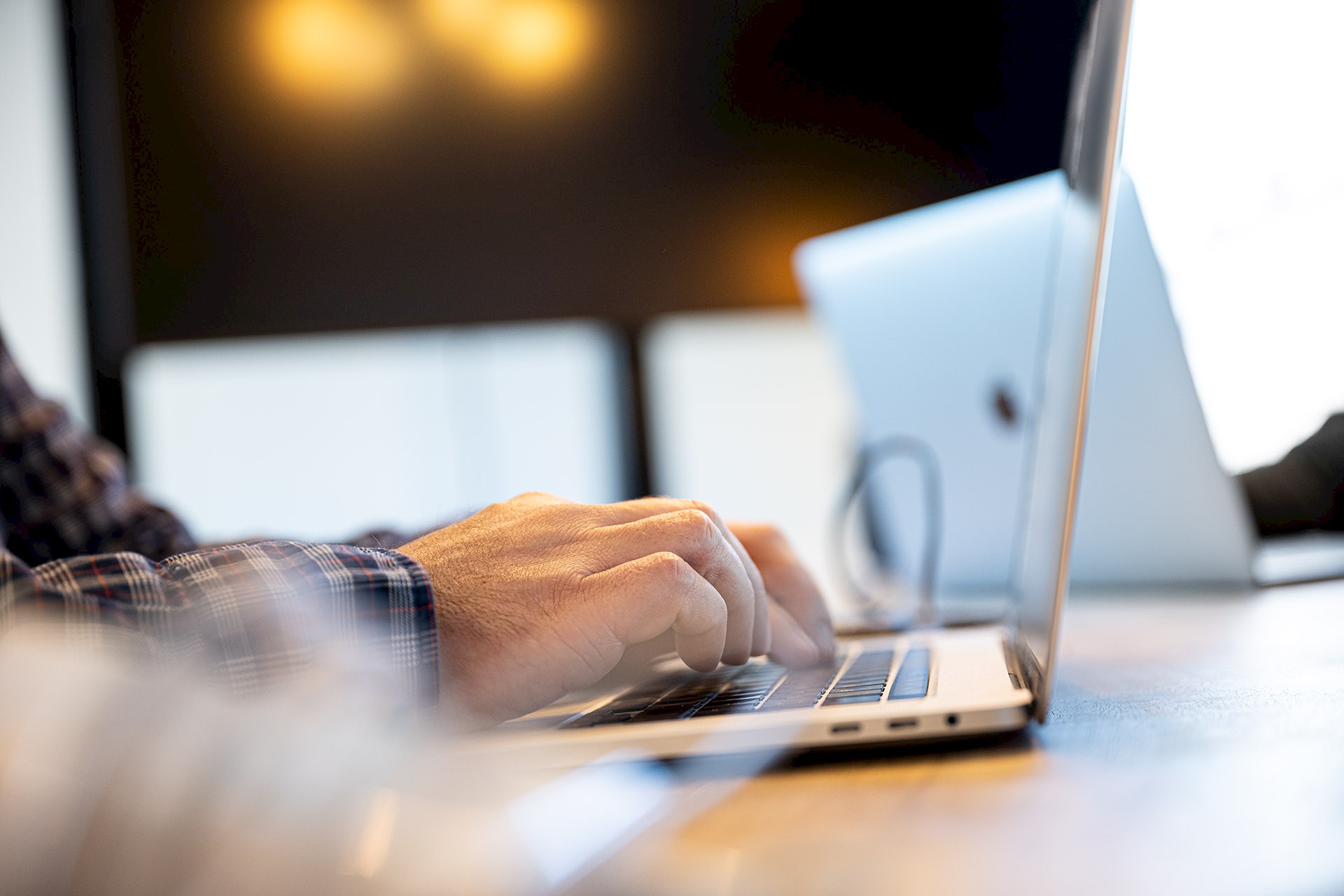 Person arbeitet an einem Laptop. Man sieht ausschließlich die Hände