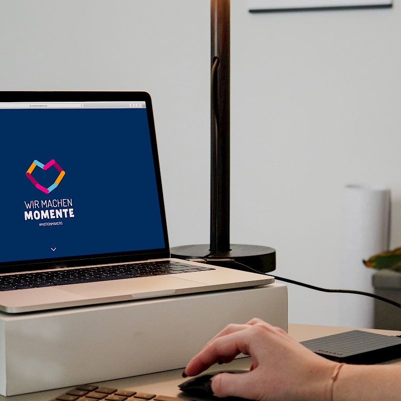 Laptop zeigt die Website von Motion Makers mit dem Slogan 'Wir machen Momente'
