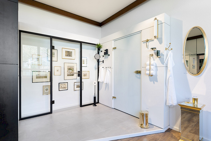 Modernes Badezimmer mit Glaswänden, goldenen Armaturen und dekorativen Bildern an der Wand