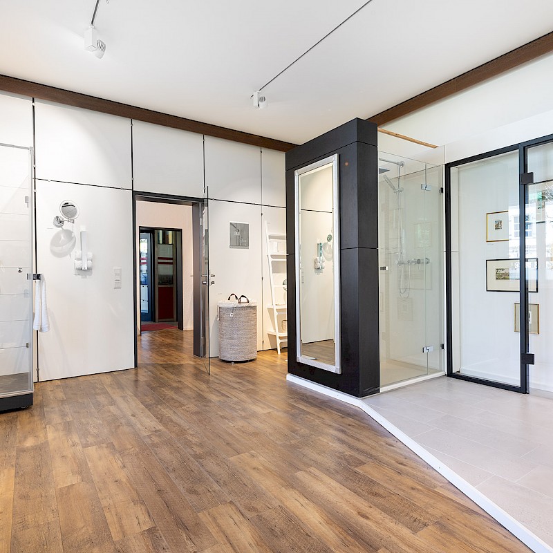 Großes modernes Badezimmer mit Glasduschen, weißen Wänden und Holzboden