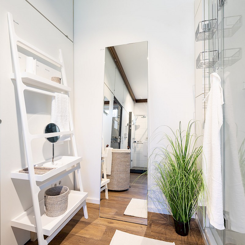 Modernes Badezimmer mit weißem Regal, großem Spiegel und Glasdusche