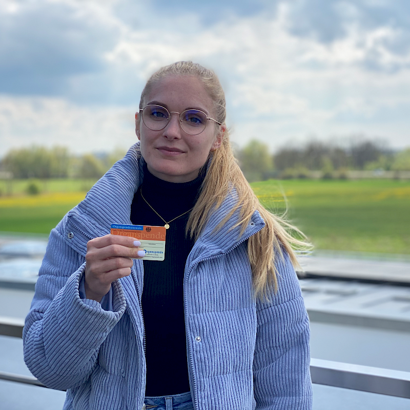 Frau im Freien hält einen Organspendeausweis.