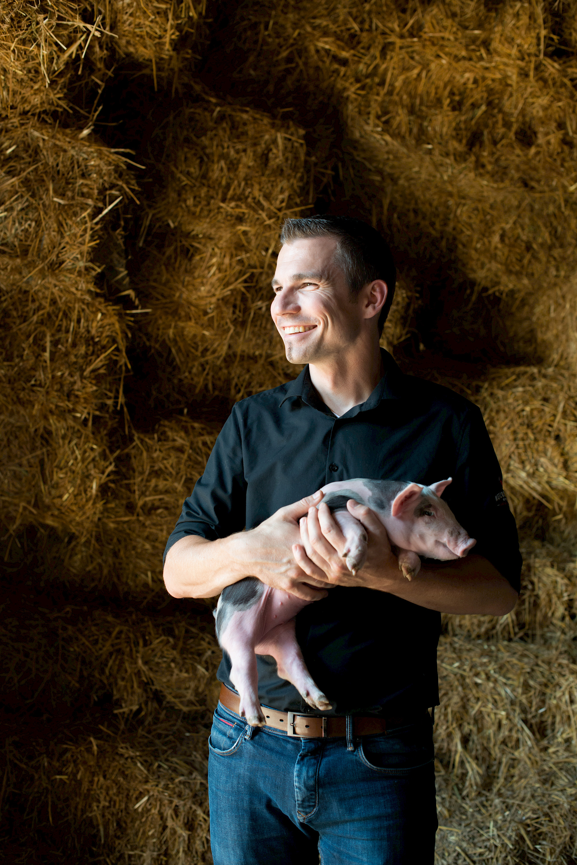 Lachender Mann der Schwein in der Hand hält.