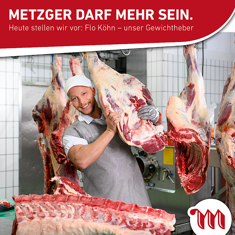 Ein Metzger trägt ein aufgeschnittenes Schweinebein und lächelt.
