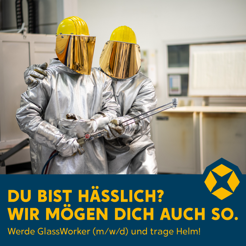 Zwei Glassarbeiter stehen vor Geräten, ihr Gesichter ist hinter einer Maske versteckt.