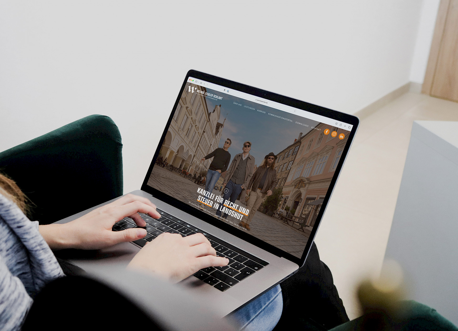 Person sitzt entspannt auf einem Sessel und tippt auf einem Laptop, auf dessen Bildschirm die Website einer Kanzlei für Recht und Steuer in Landshut zu sehen ist.