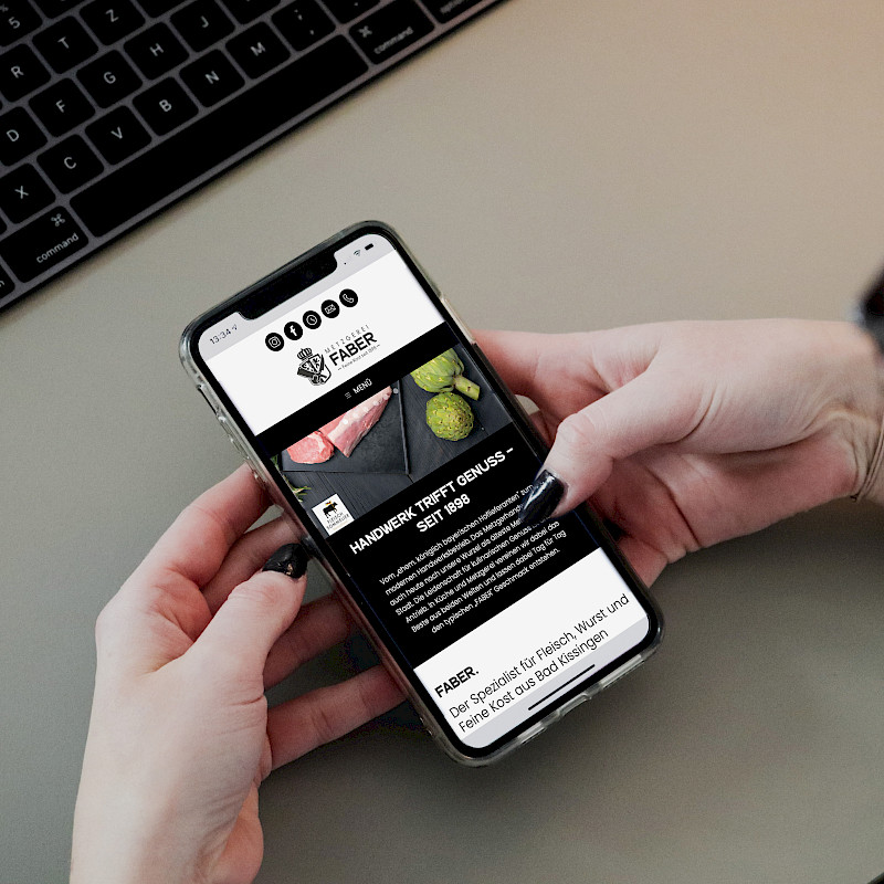 Frau hält ihr Smartphone in der Hand auf der die Metzgerei Faber Website geöffnet ist