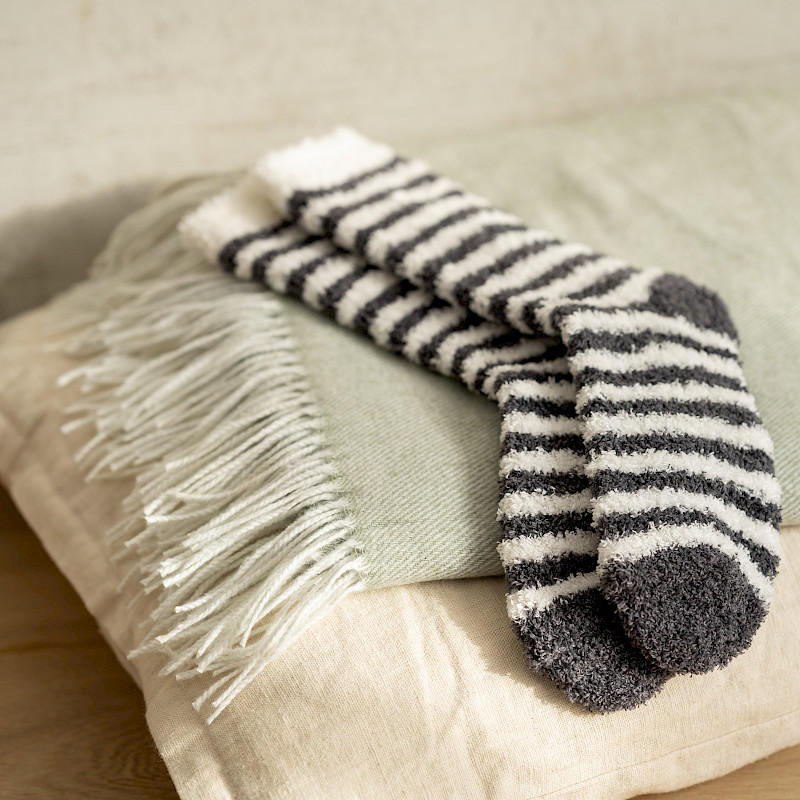 Weiß-Grau gestreifte Socken liegen auf einem kissen