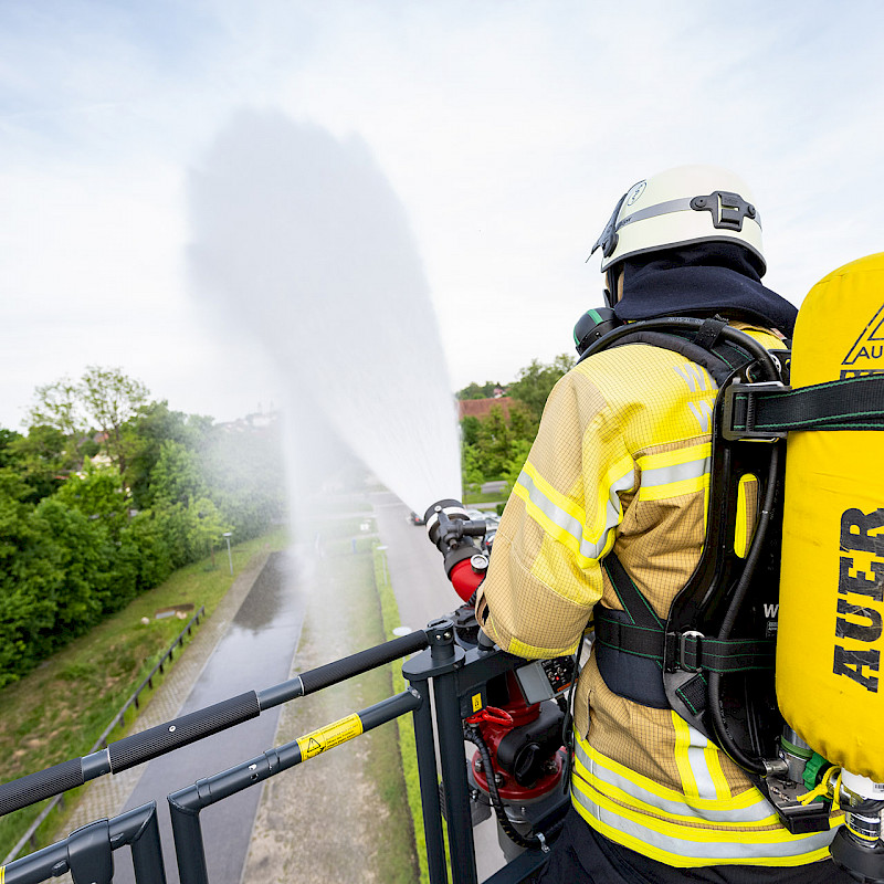 Ein Feuerwehrmann benutzt den Wasserlöscher in seiner Uniform.