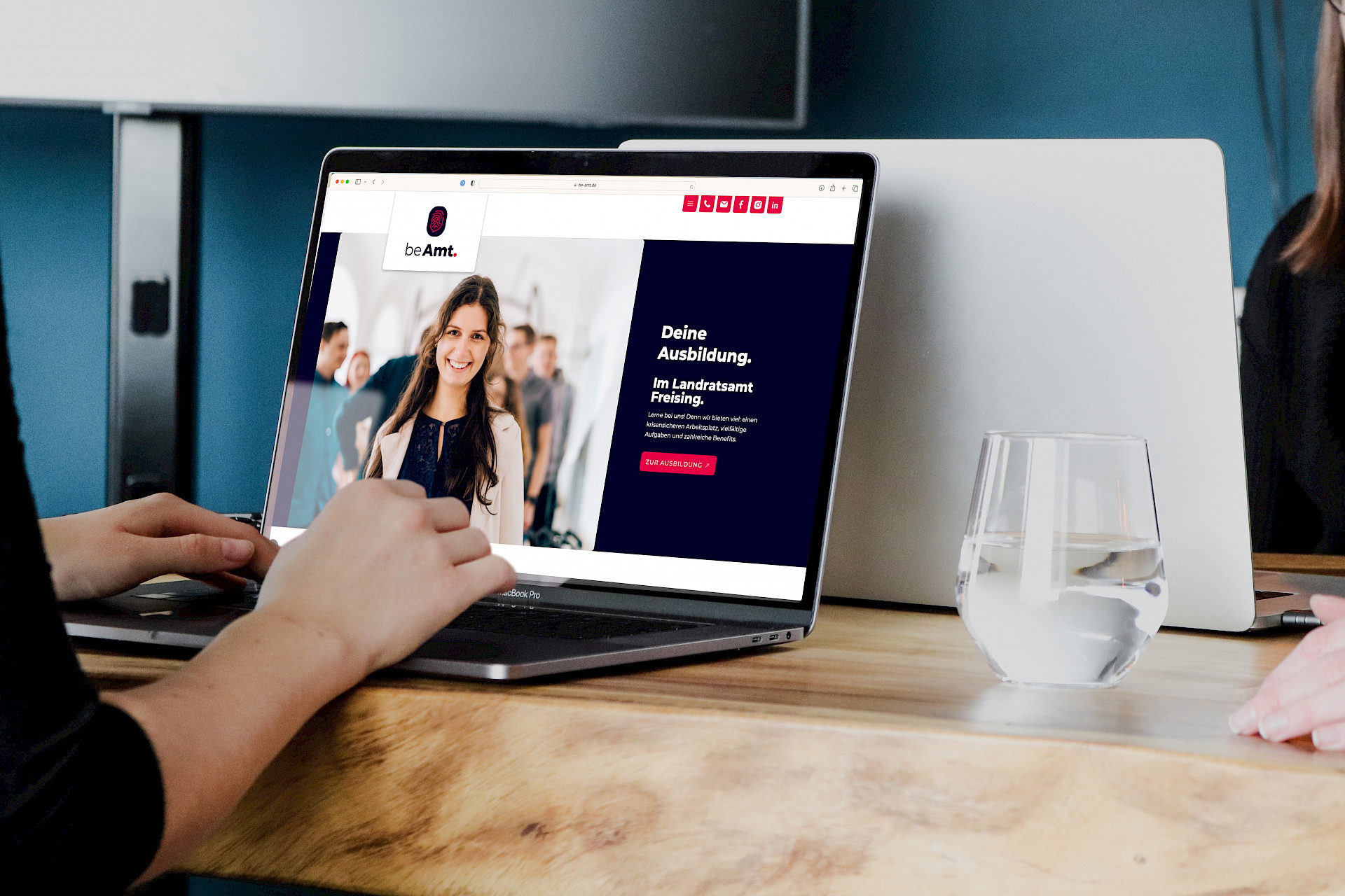 Zwei Personen arbeiten an einem Laptop, der eine Website über Ausbildungsmöglichkeiten im Landratsamt Freising zeigt