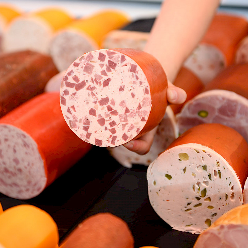 Verschiedene angeschnittene Wurstsorten nebeneinander in einer Auslage.