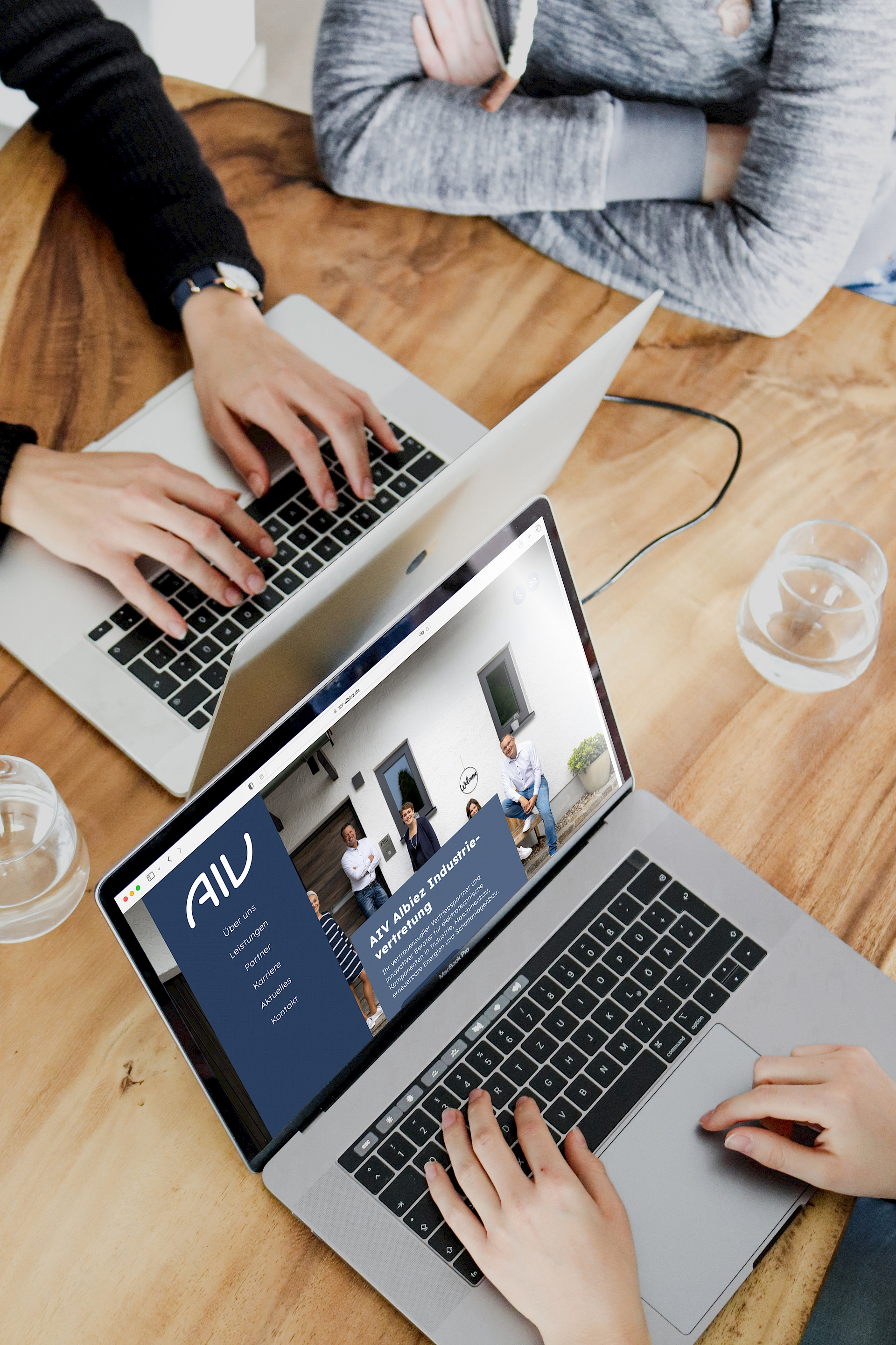 Zwei Personen sitzen an ihren Laptops, daneben sitzt noch eine dritte Person