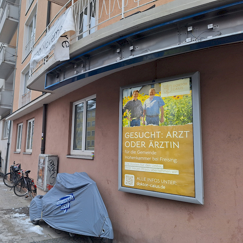 Werbeplakat an einer Hauswand, das einen Arzt oder eine Ärztin für eine Praxis in Hohenkammer bei Freising sucht