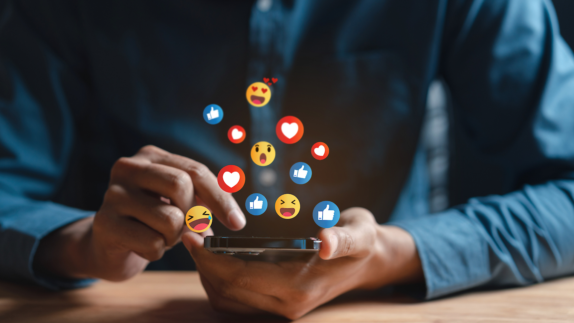 Person die Ihr Handy in der Hand hält. Aus dem Handy kommen Emojis und Herzen