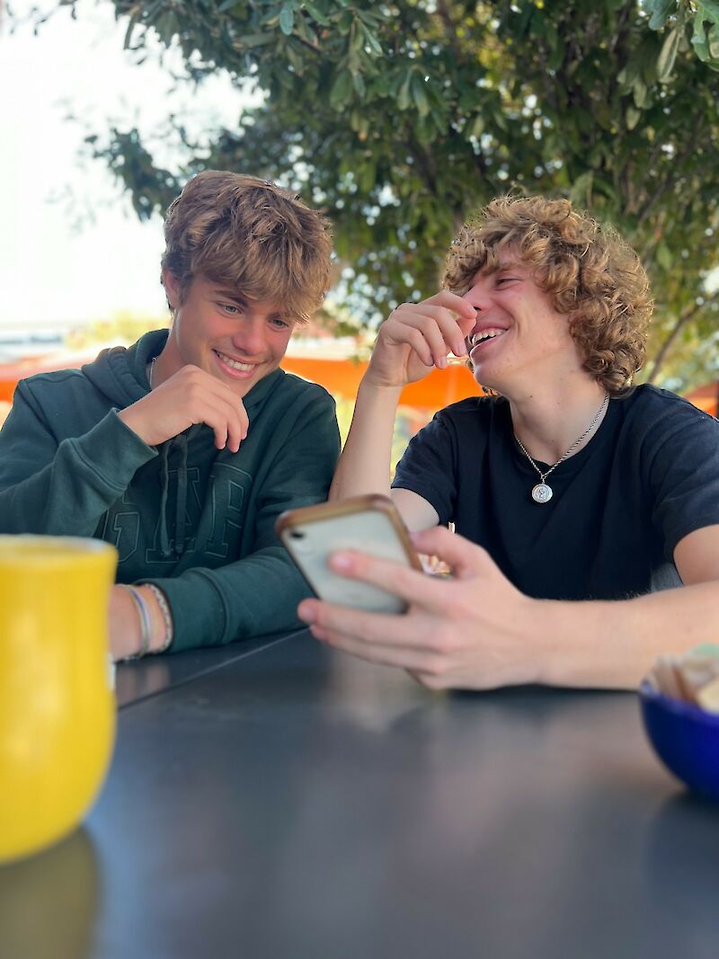 Zwei Jugendliche die sich etwas auf einem Handy anschauen und darüber lachen